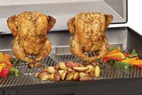 Two chickens being slowed cooked on a grill.